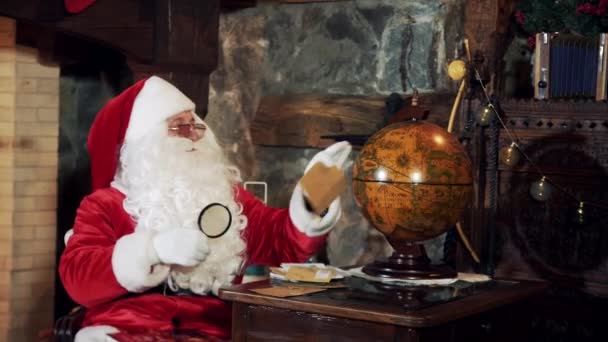 Санта Смотрит Глобус Сидя Своей Резиденции Санта Белой Бородой Красном — стоковое видео