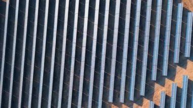 Güneş panellerinin günbatımındaki görüntüsü karanlık alanlarda bir sırada duruyor. Yeşil enerji peyzajı elektrik gücü. Kamera döndür.