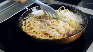 Pastırmalı kremalı makarna yapıyorum. Şef kızartma tavasında spatulayla enfes spagetti pişiriyor. İtalyan mutfağı. Yakın plan..