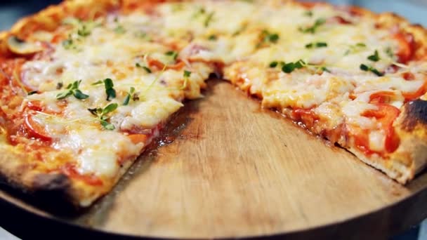 トマトとホットイタリアのピザ チーズとハーブ 木製のテーブルの上に回転します ピザをスライスに切る — ストック動画