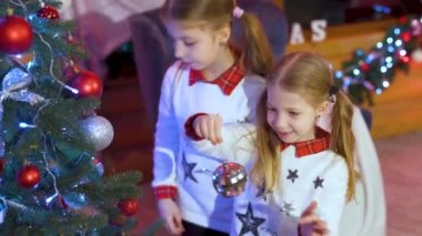 Happy little girls sisters decorating christmas tree with balls. children decorating a Christmas tree. Christmas spirit. Holidays and celebrations concept.