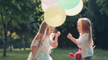 Balonlu ve kelebek ağlı iki tatlı kız parkta tatilde taş-kağıt-makas oynuyorlar. Doğada sabun köpükleri.