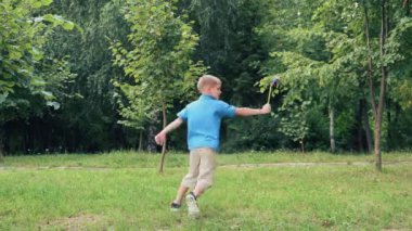 Mavi tişörtlü mutlu bir çocuk gülümsüyor, oyuncak bir yel değirmeniyle oynuyor, parktaki çimlerde koşuyor. Güneşli bir yaz günü. Rüzgar çarkı ya da yel değirmeni oyuncağı