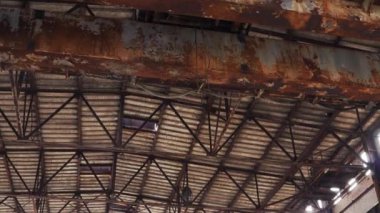 Terk edilmiş bir fabrika hangarında eski paslı metal tavan. Metal kirişler, kırık endüstriyel vinç yapıları..