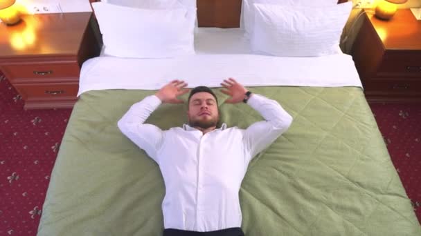 Jeden Mężczyzna Białej Koszuli Leży Łóżku Pokoju Hotelowym Ręce Głowę — Wideo stockowe