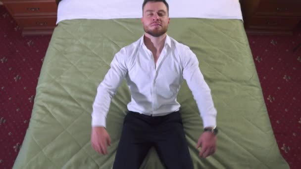 疲惫的男商人穿着白衬衫和裤子 辛苦劳作了一天后倒在床上 在酒店房间休息 顶部视图 — 图库视频影像