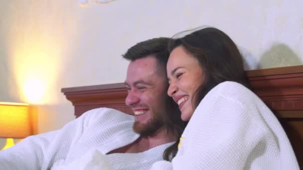 Fröhlich Lachende Junge Paare Bademänteln Einem Hotelzimmer Liegen Auf Dem — Stockvideo