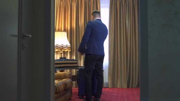 Бізнесмен Костюмі Валізою Колесах Перевіряється Готельному Номері Чоловік Знімає Піджак — стокове відео