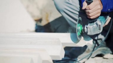 İşçi taşları öğütücüyle kesiyor. Testerenin yaptığı taş tozu. Kum taşının dekoratif işleme fabrikası.