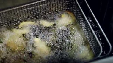 Kaynar yağda ince dilimler halinde patates kızartması pişirmek. Yakın plan. Yavaş çekim