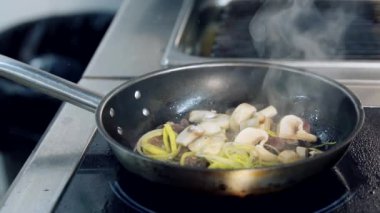 Kızarmış şampiyon mantarı kızartma tavasında. Mutfak sobasında spatulayla yemek karıştırmak. Yavaş çekim