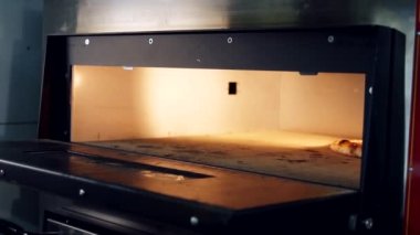 Şef pizzayı fırından çıkarmak için bir pizza küreği kullanır. Restoran mutfağında elektrikli fırının kapısını açmak..