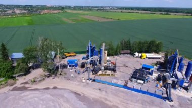 Asphalt bitkisi sahada. Teknik tesisler, metal yapılar, fabrikadaki bijon varilleri. Kamyonlar ve ekipmanlar otoparkta. Bir yol kaldırım fabrikasının havadan görünüşü.