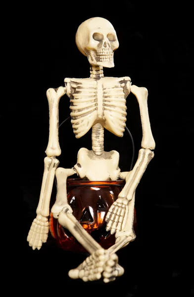 Скелет сидит на банке из-под тыквы — стоковое фото