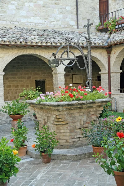 Poço medieval antigo para a colheita de água com vasos de flores — Fotografia de Stock