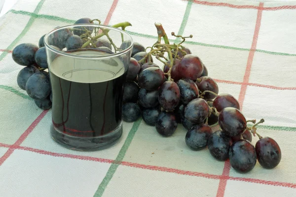 Copa llena de vino y un ramo de uvas negras maduras — Foto de Stock