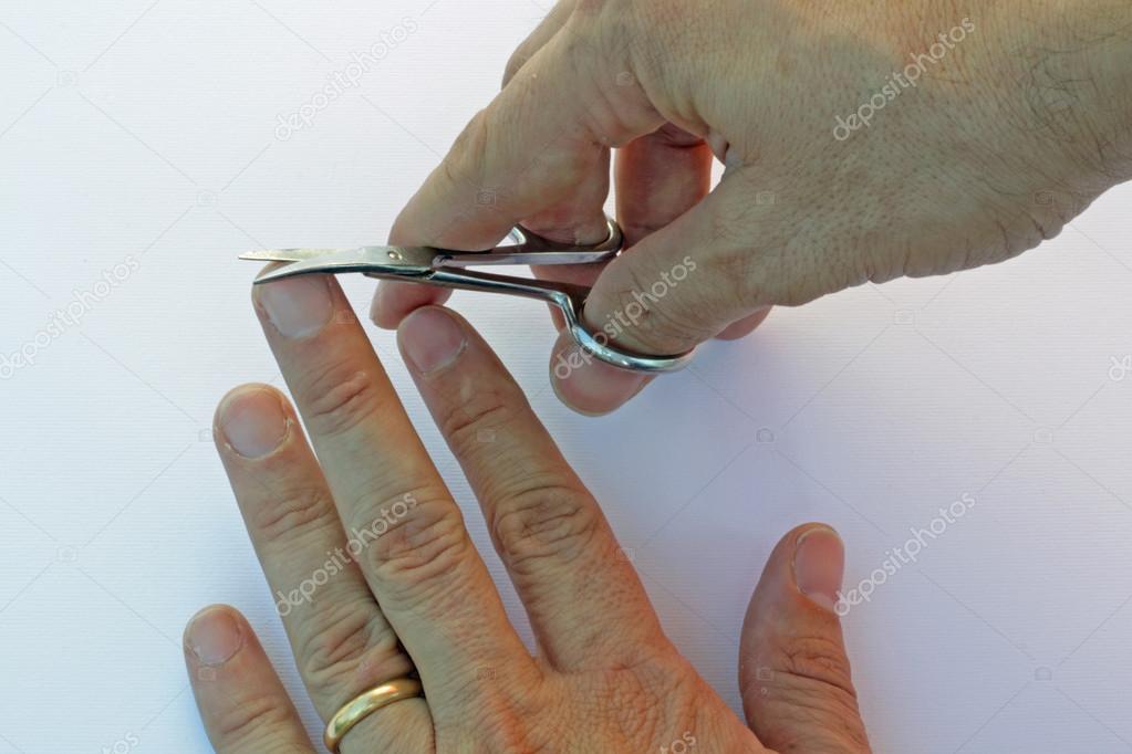 hands of an adult man who cuts the nail of the middle finger