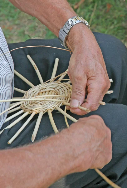 Grandes mãos de artesão especialista como ele trabalha para fazer um baske de vime — Fotografia de Stock