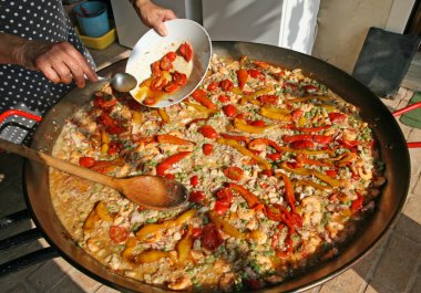 Balık ile büyük tava pirinç için kırmızı domates ekledikçe cook
