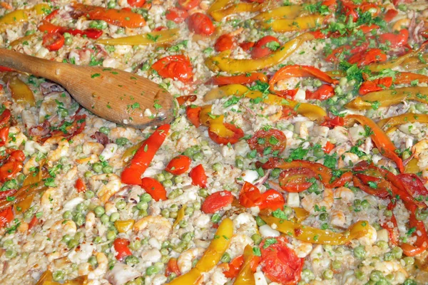 Arroz de marisco con tomates y guisantes y una cuchara de madera —  Fotos de Stock