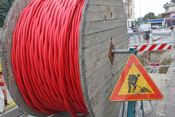 Lavori stradali e una bobina di filo con il cartello stradale — Foto Stock