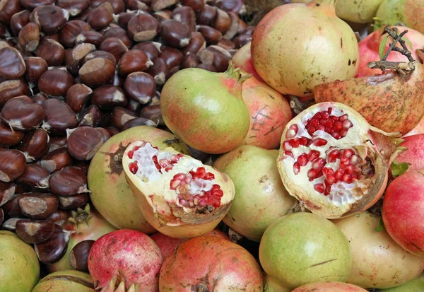 Klassieke herfst vruchten met vele rijp kastanjes en granaatappels — Stockfoto