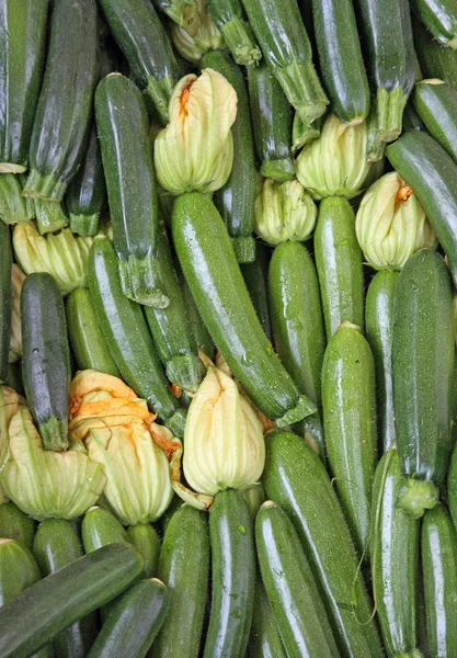 Čerstvé zelené cukety v částech k prodeji na trhu se zeleninou — Stock fotografie