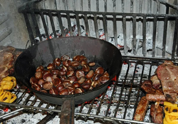 Frying pan with lots of roasted chestnuts on an open fire — Stock Photo, Image