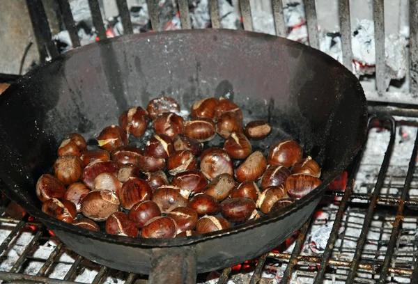 Pfanne mit vielen gerösteten Kastanien auf offenem Feuer — Stockfoto