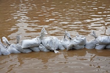 Wall of sandbags to fend off raging river clipart