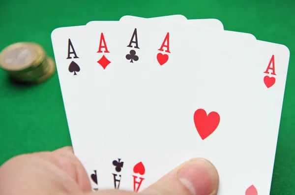 Χέρι με πόκερ άσων σε ένα πράσινο τραπέζι παιχνίδι — Φωτογραφία Αρχείου