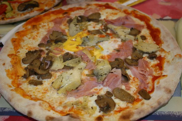 Välsmakande pizza med skinka, ost och kronärtskockor — Stockfoto