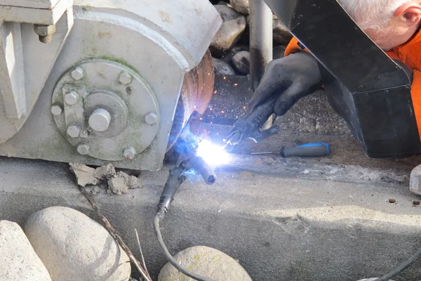 Enquanto trabalhador firme um pedaço de ferro com ferro de solda — Fotografia de Stock