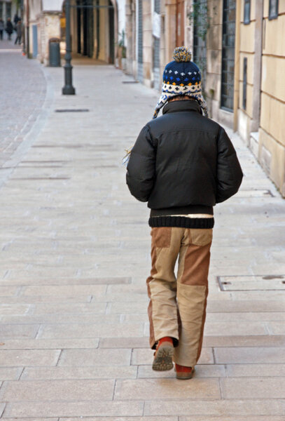 lonely child with jacket and wool Cap walk along the deserted ro