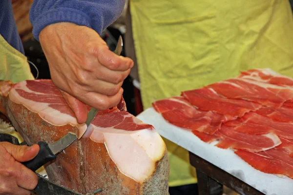 Butcher's hand and knife during preparation of raw ham — Stock Photo, Image