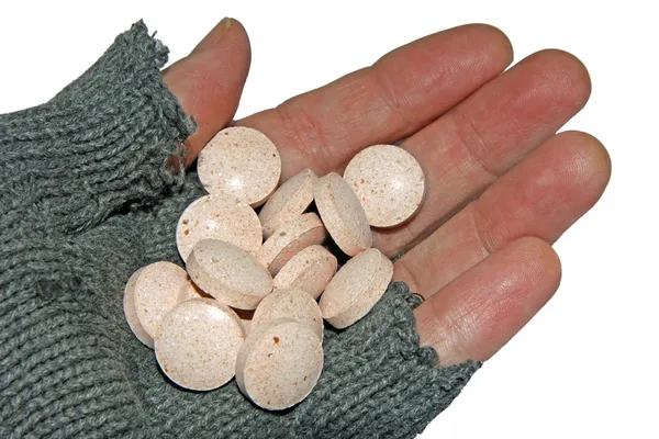 Hand of poor man holding a handful of tablets — Stock Photo, Image