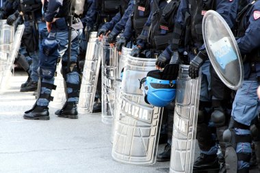 policemen in riot gear with shields and helmets and helmets duri clipart