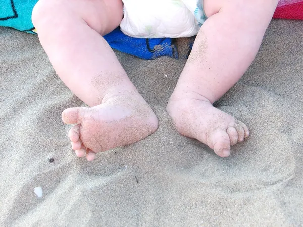 Маленькие ножки с подгузником на песке пляжа — стоковое фото
