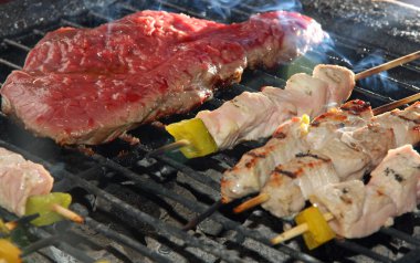 skewers of meat and beef fillet on the barbecue in the garden clipart