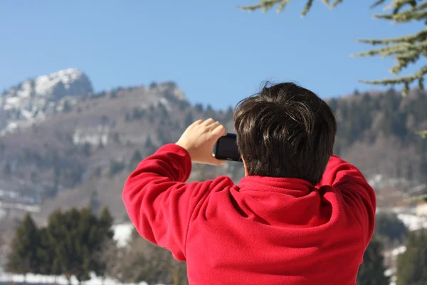 Boy v červený svetr, že fotografoval vrcholu hory — Stock fotografie