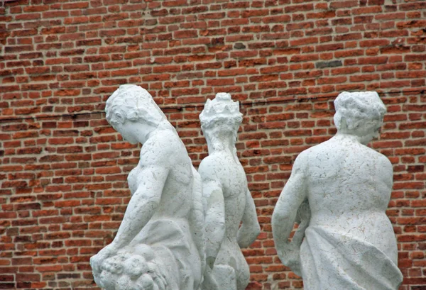 Estatuas de mármol blanco y fondo de ladrillo rectangular rojo —  Fotos de Stock