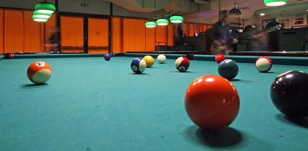 Salle de billard fumé avec des billes sur le tapis et des joueurs attentifs — Photo