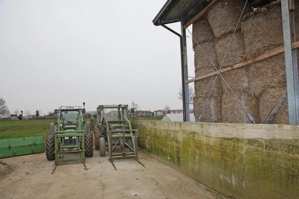 Zwei grüne Traktoren, die auf einem Bauernhof im Freien geparkt waren — Stockfoto