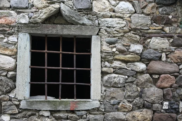 Window with a metal grid on an old stone barn — Stock Photo, Image