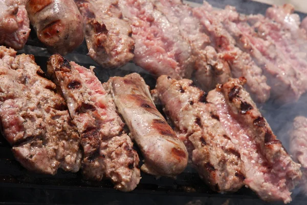 Worstvlees en steak in een gigantische barbecue in de tuin — Stockfoto