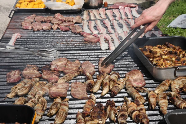 Cozinhe enquanto cozinha em uma grade de um churrasco ao ar livre para grelhar — Fotografia de Stock