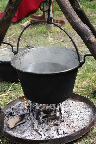 Ancien pot médiéval avec de l'eau sur le feu et des trépieds pour suppo — Photo