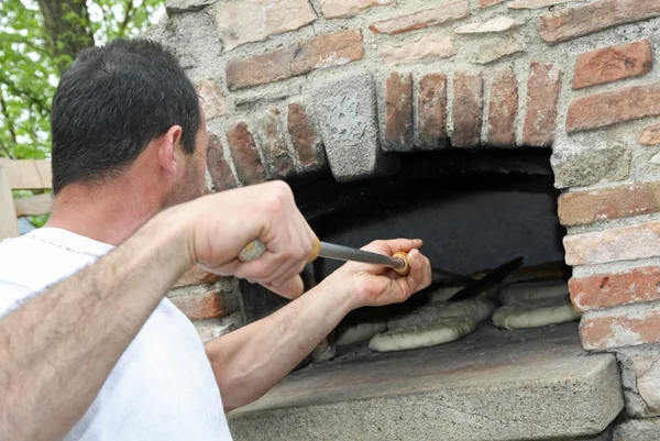 Panadero musculoso al hornear pan en un horno de leña — Foto de Stock