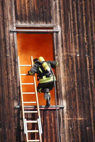 Bombeiros corajosos com cilindro de oxigênio entra em uma casa através — Fotografia de Stock