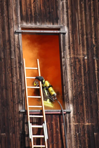 Bombeiros corajosos com cilindro de oxigênio entra em uma casa através — Fotografia de Stock